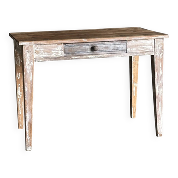 Vintage table made of raw wood with a distressed white base.