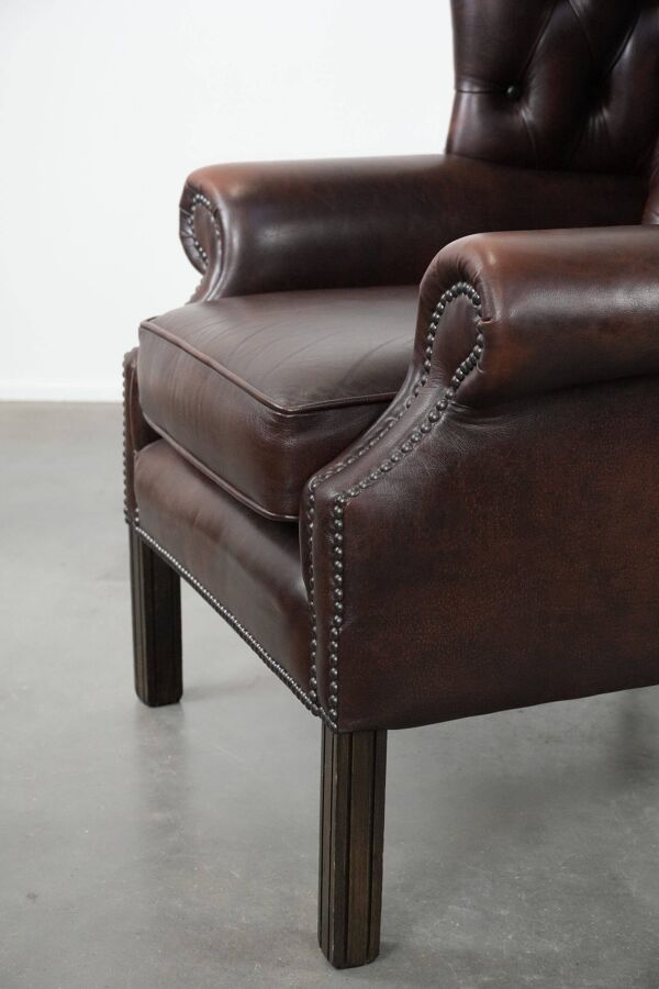 Fauteuil à oreilles Chesterfield en cuir de vachette marron dans le style anglais.