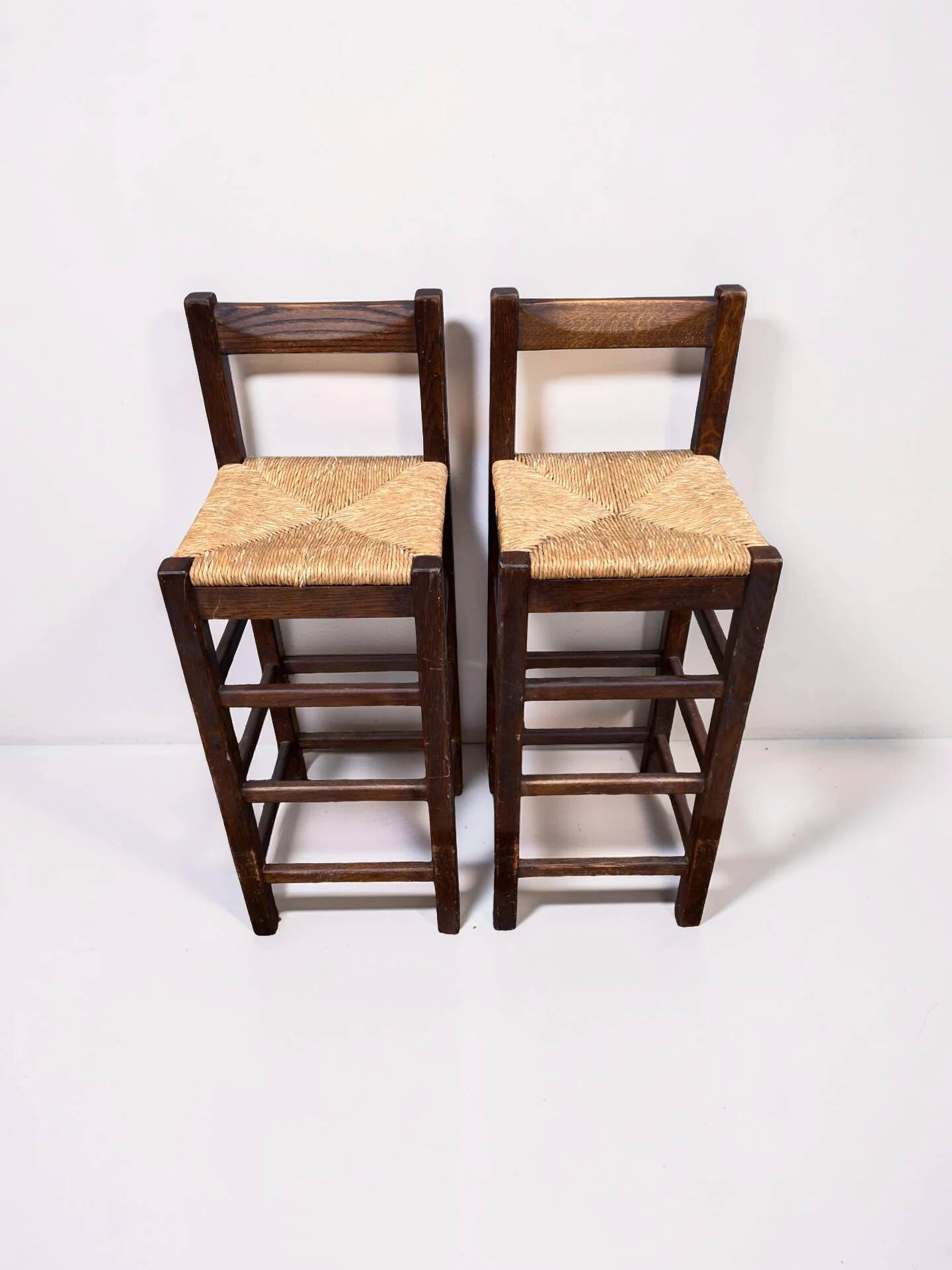 Set of 2 vintage wooden bar stools with woven straw seats.