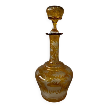 Amber bohemian glass liqueur carafe decorated with a stag in the forest.
