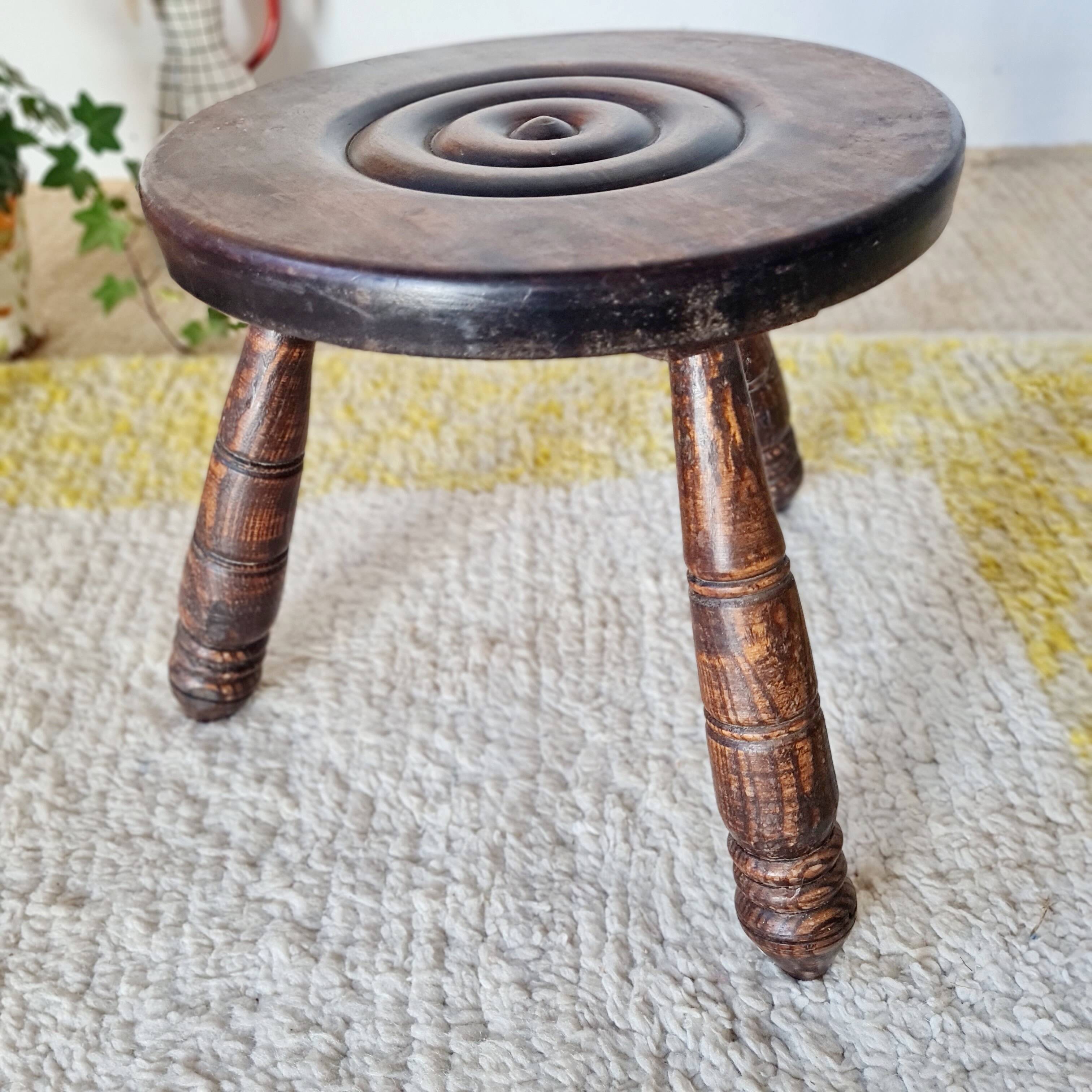Small brutalist tripod stool made of turned wood.