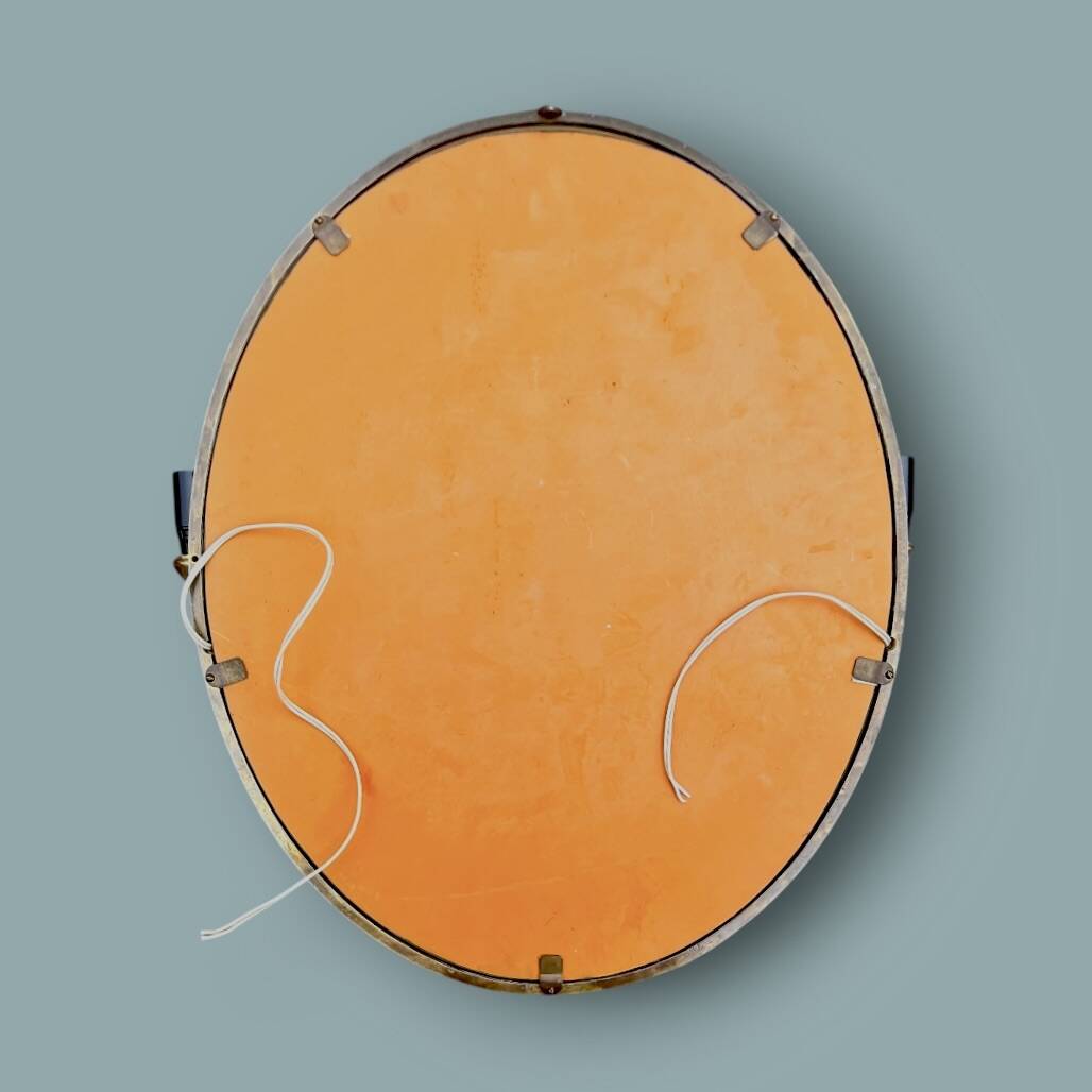 Oval wall mirror in gilded brass with double sconces – 1950s/60s
