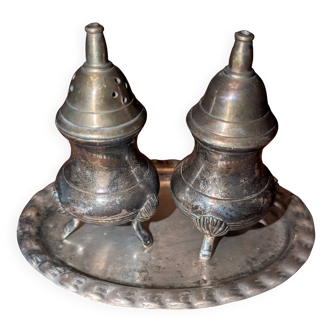 Vintage salt and pepper shaker duo in silver-plated metal on a boat-shaped tray.