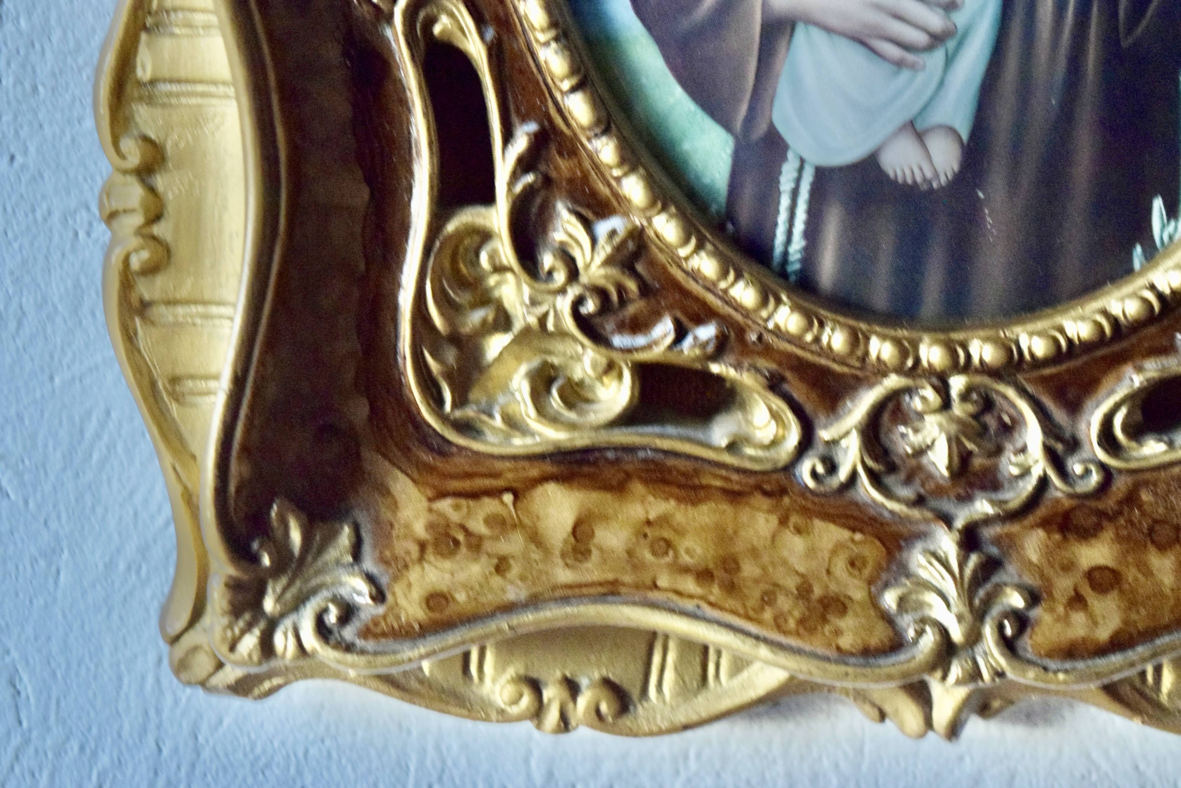 Old religious light frame in gilded stucco and curved glass