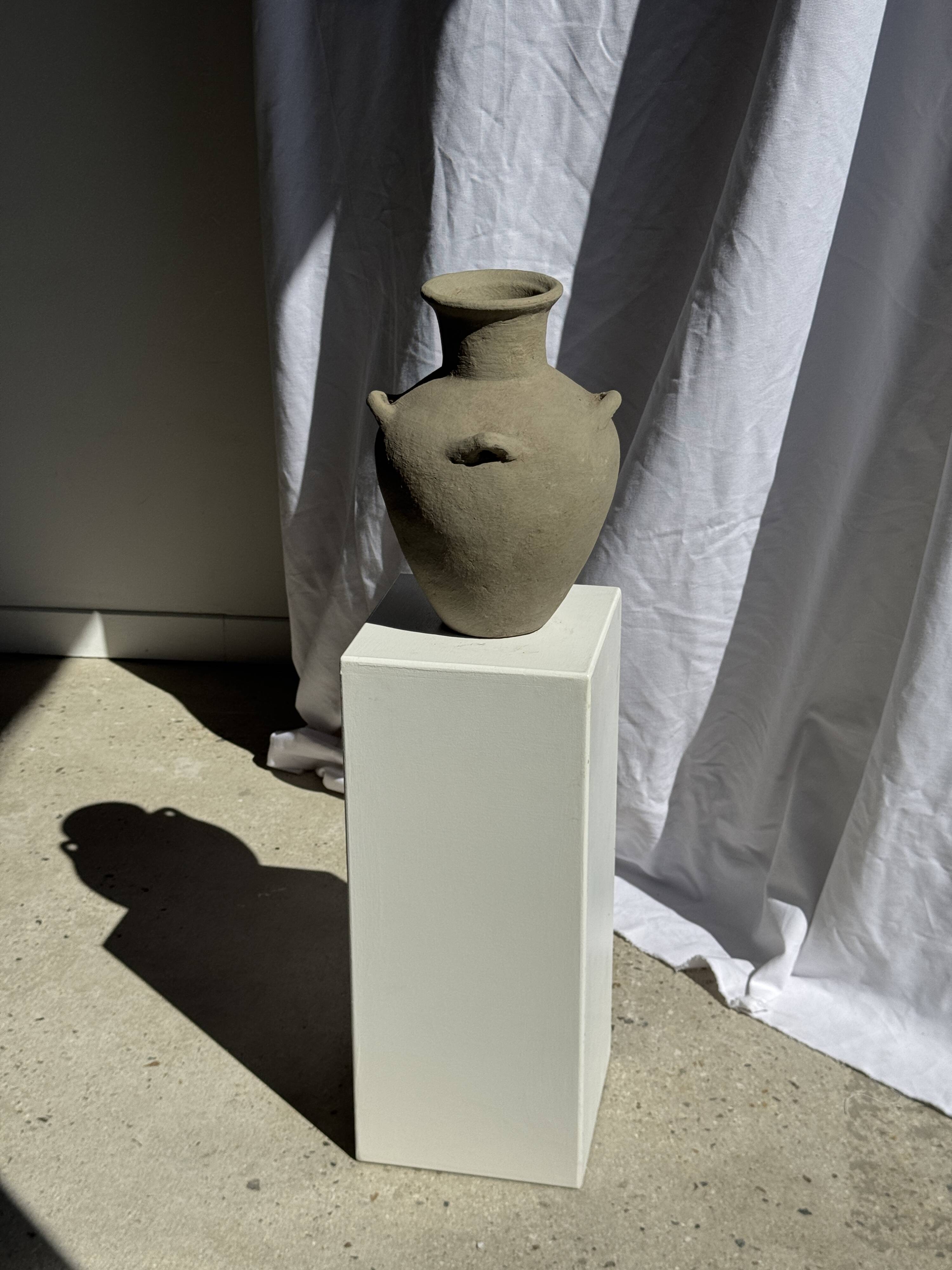 Light beige-grey Indonesian terracotta vase with 4 small handles and a high neck.