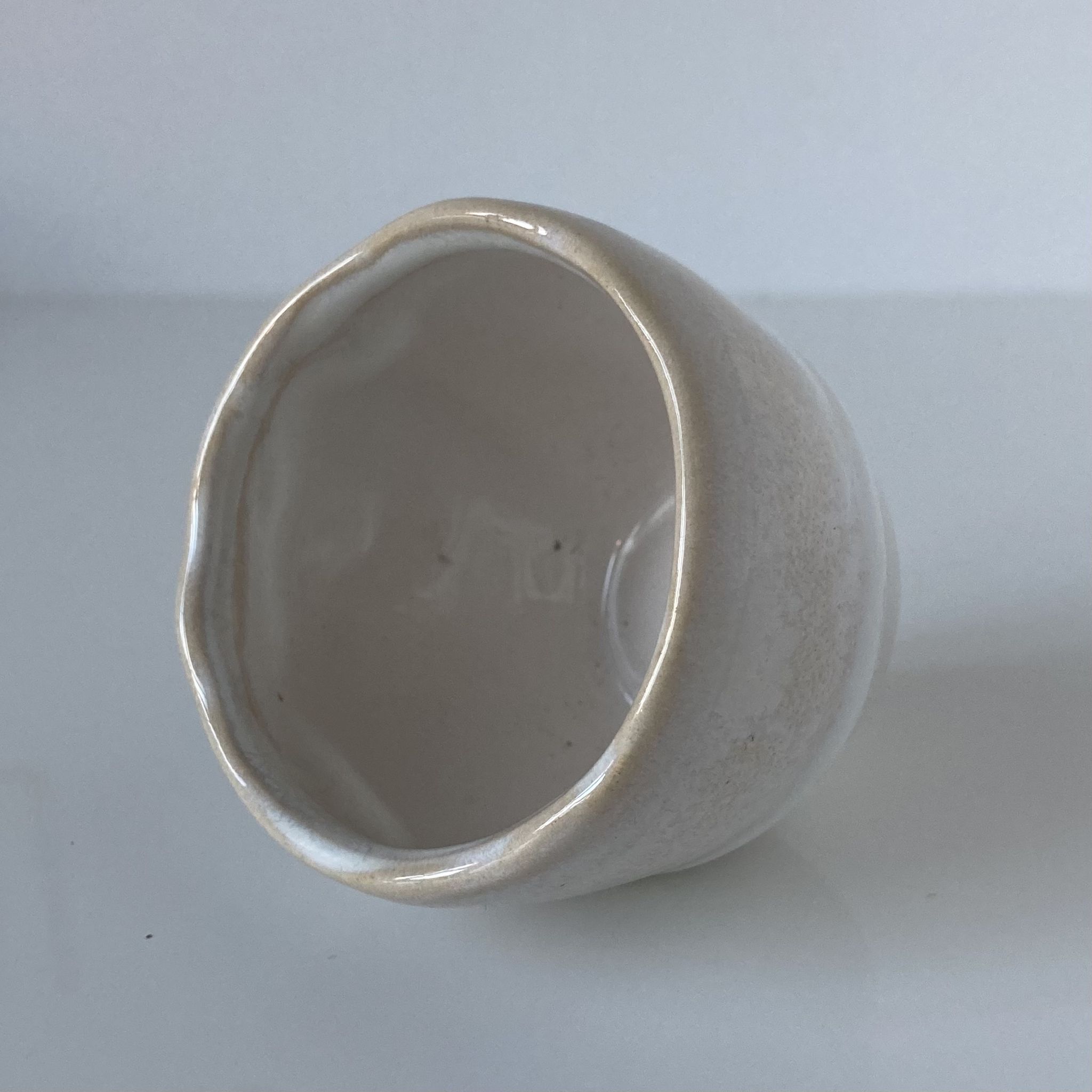 Meeting of three artist's ceramic objects including two pots and a cream covered bowl