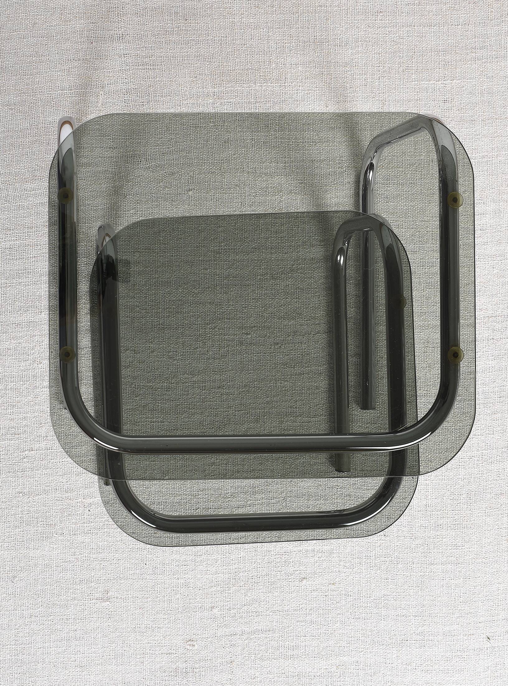 Pair of nesting tables in smoked glass and chrome legs.