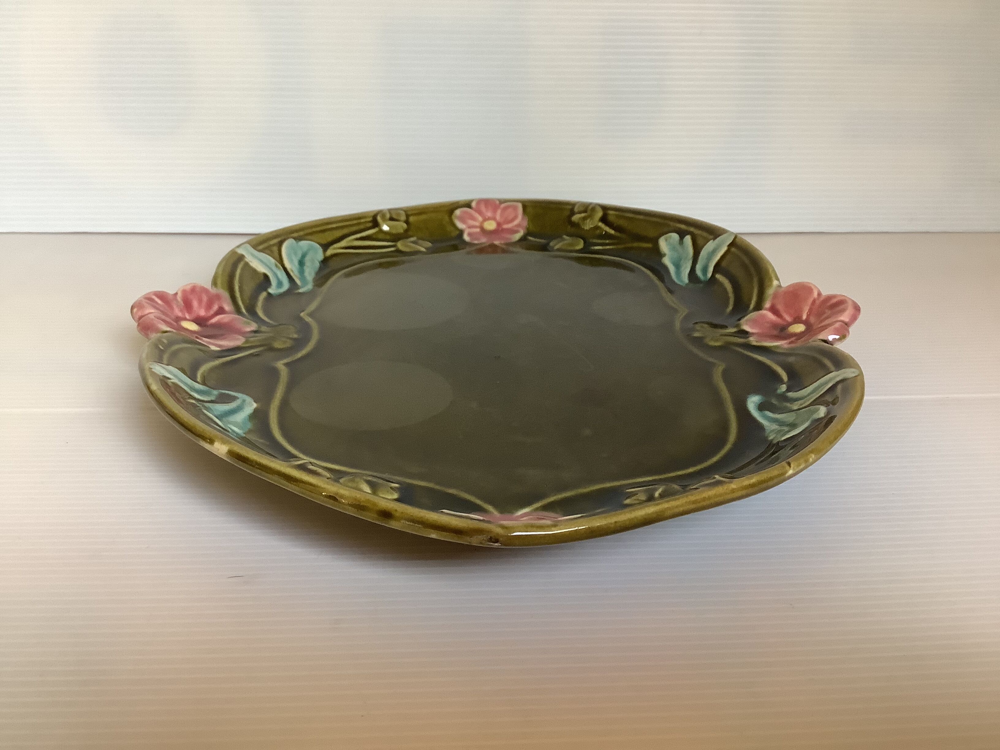 Old khaki green earthenware dish and pink flowers