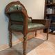 Antique carved wooden bench with green upholstered seat and backrest.