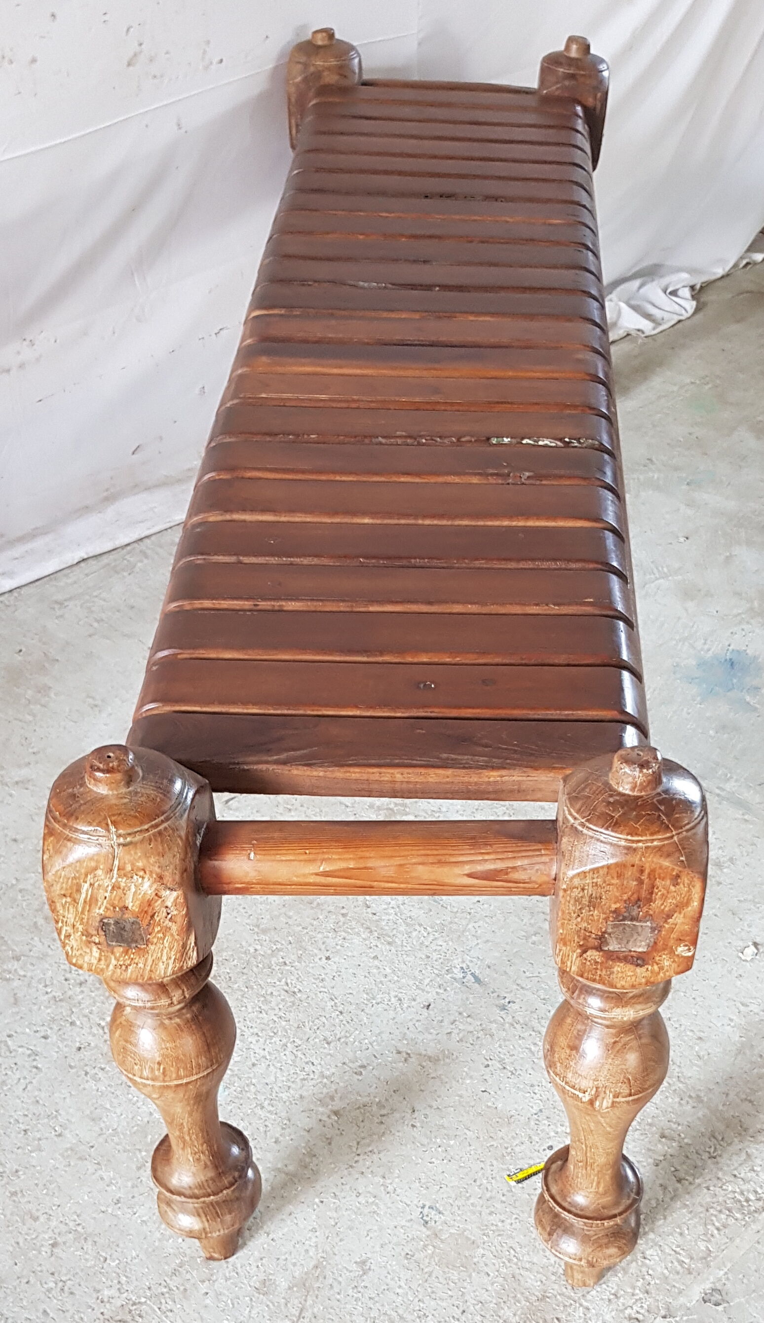 Bench with slats and feet of charpoy beds in teak