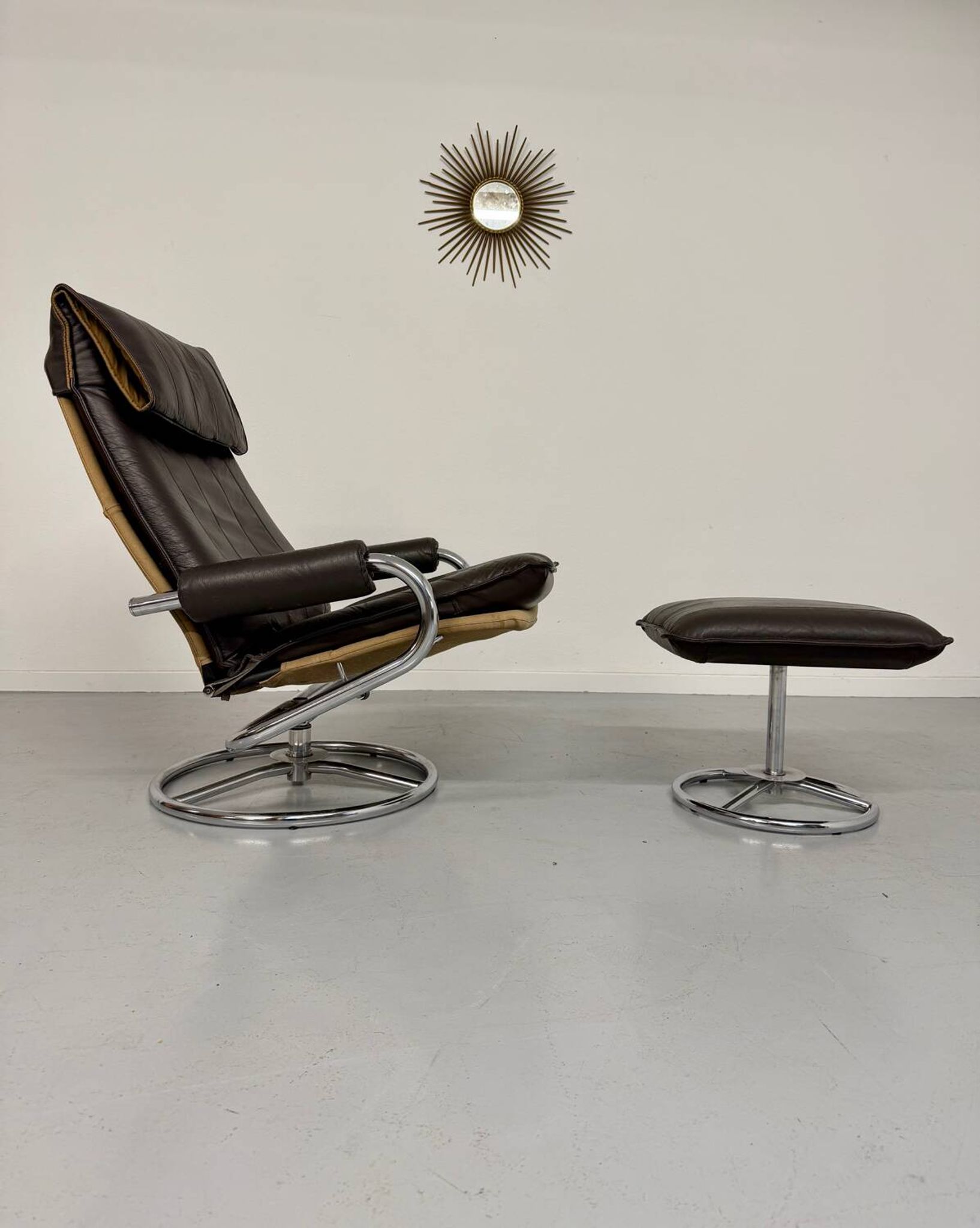 Vintage leather reclining armchair and its 1970s designer ottoman.
