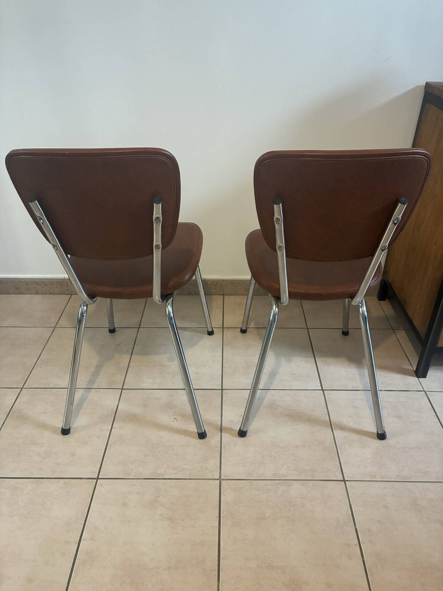 Two brown faux leather chairs.