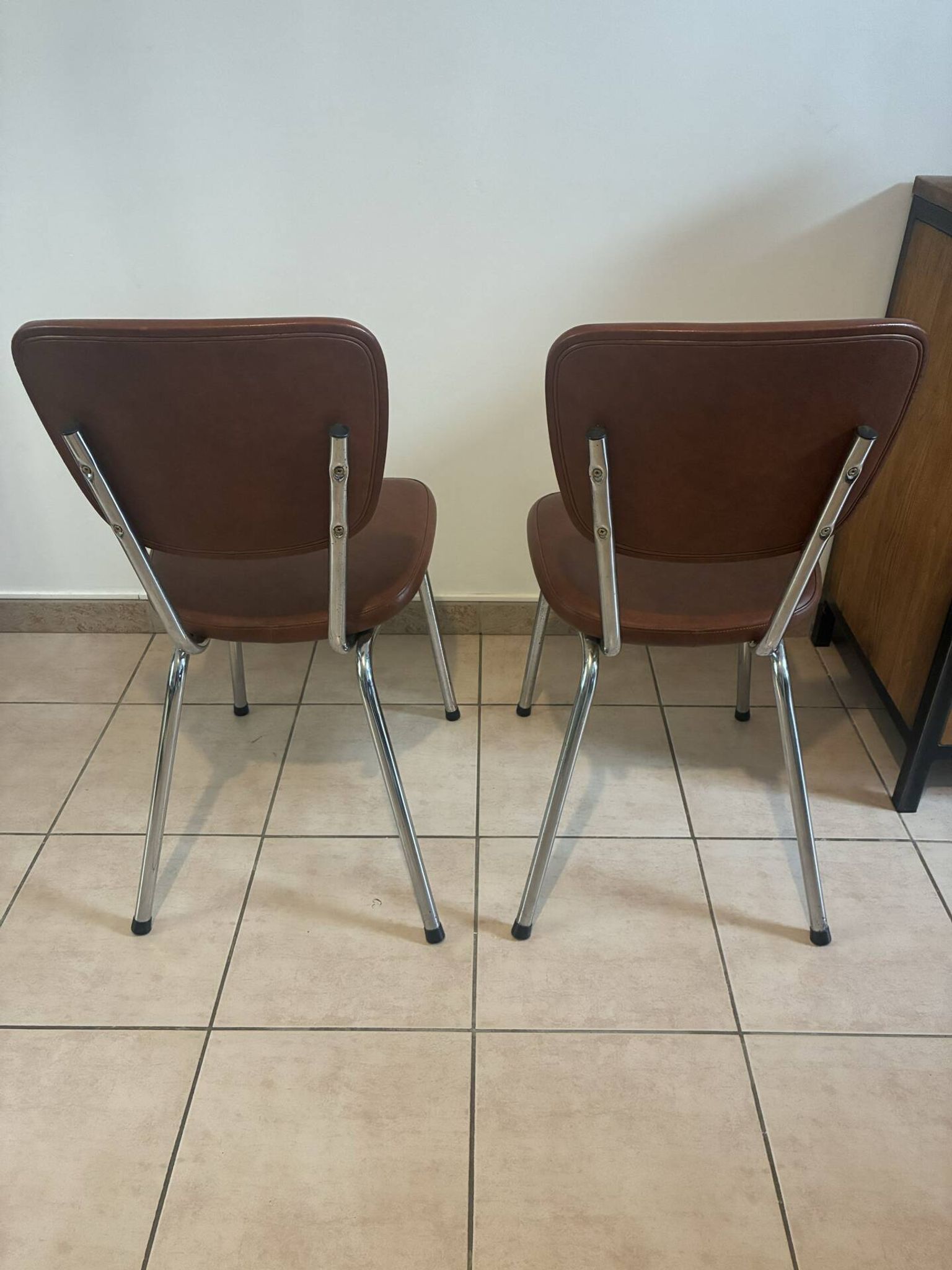 Two brown faux leather chairs.