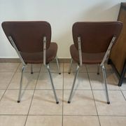 Two brown faux leather chairs.