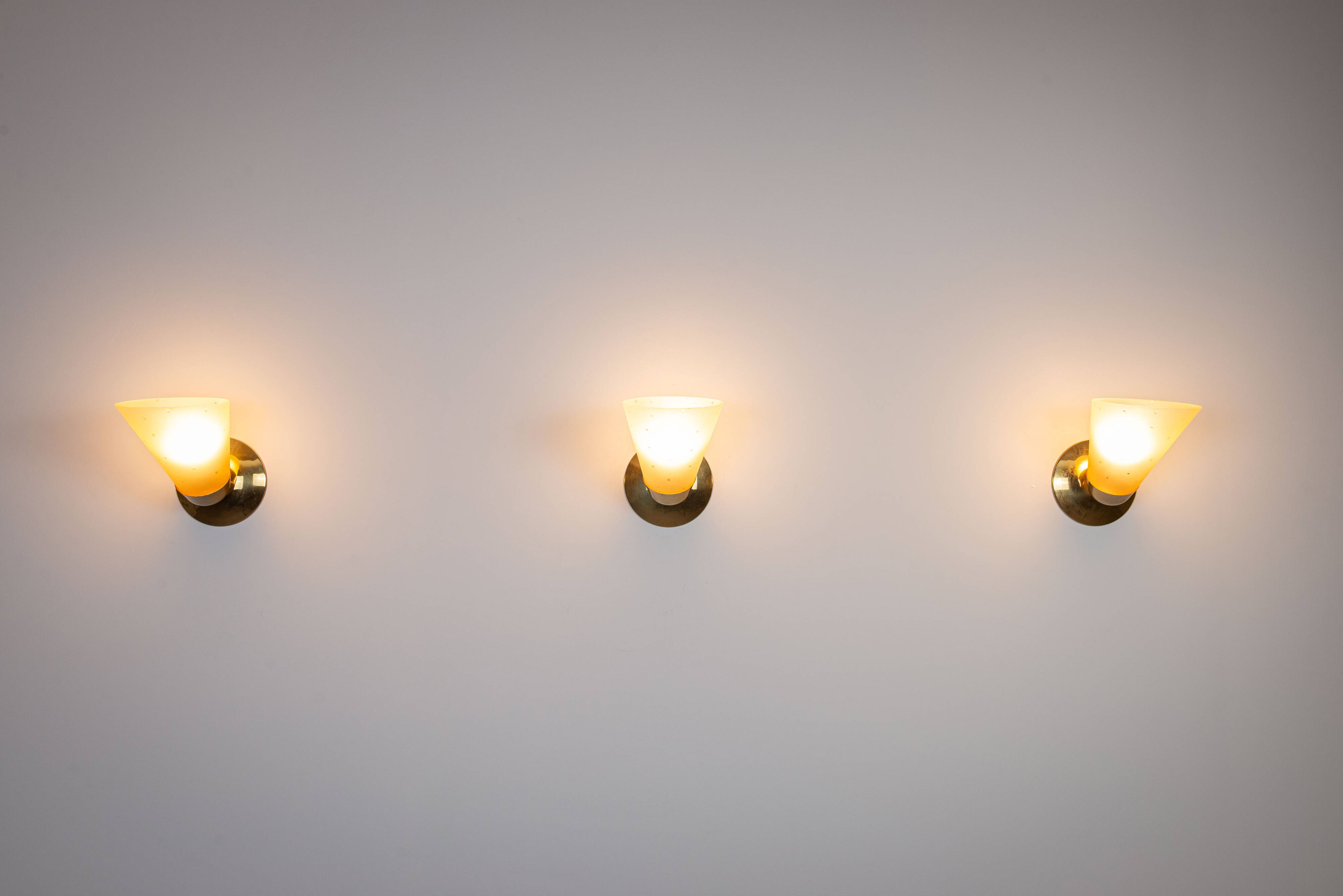Set of three brass sconces with decorated yellow glass shades