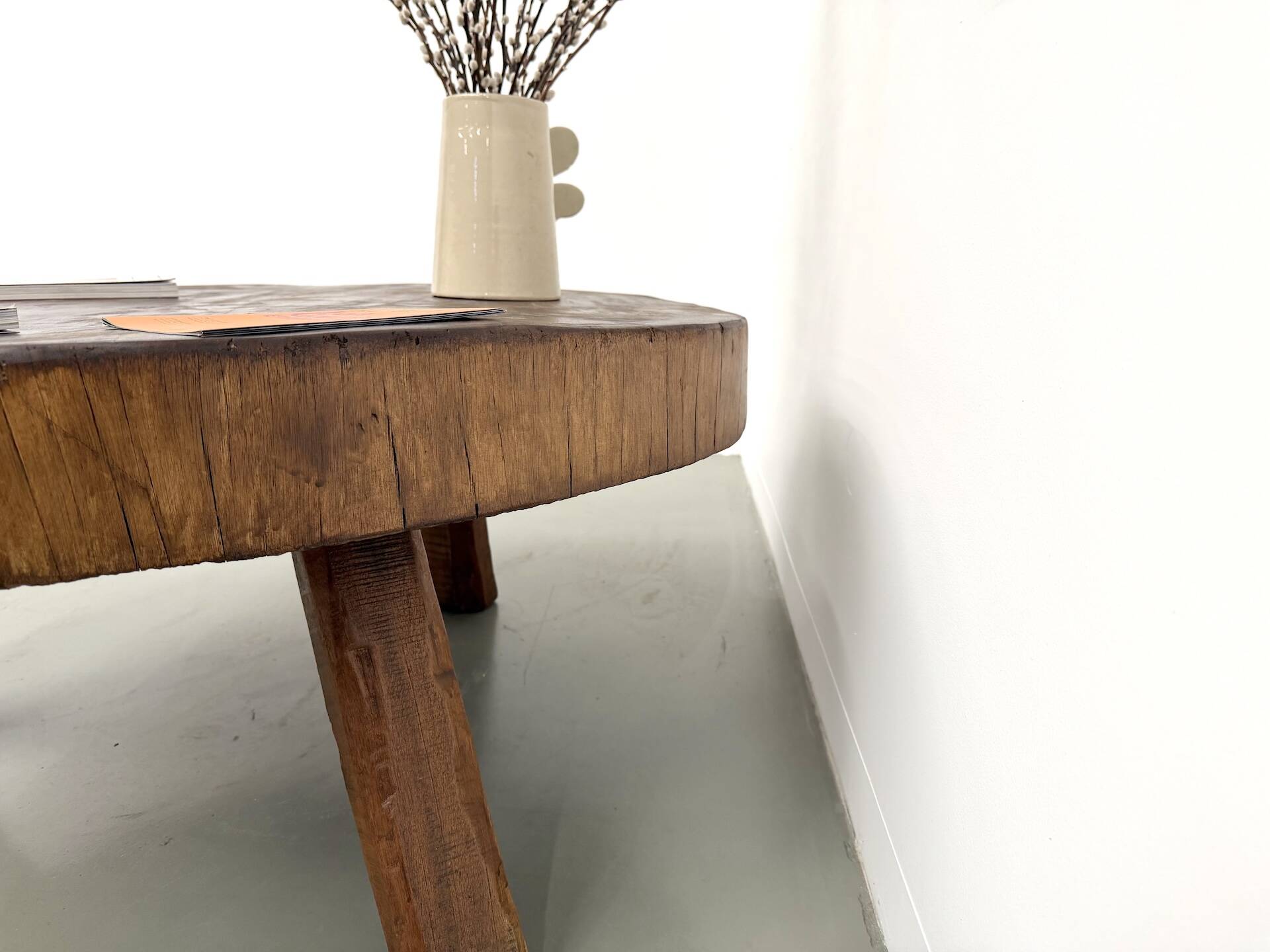 Brutalist coffee table in solid teak, monolithic slab, tripod base.