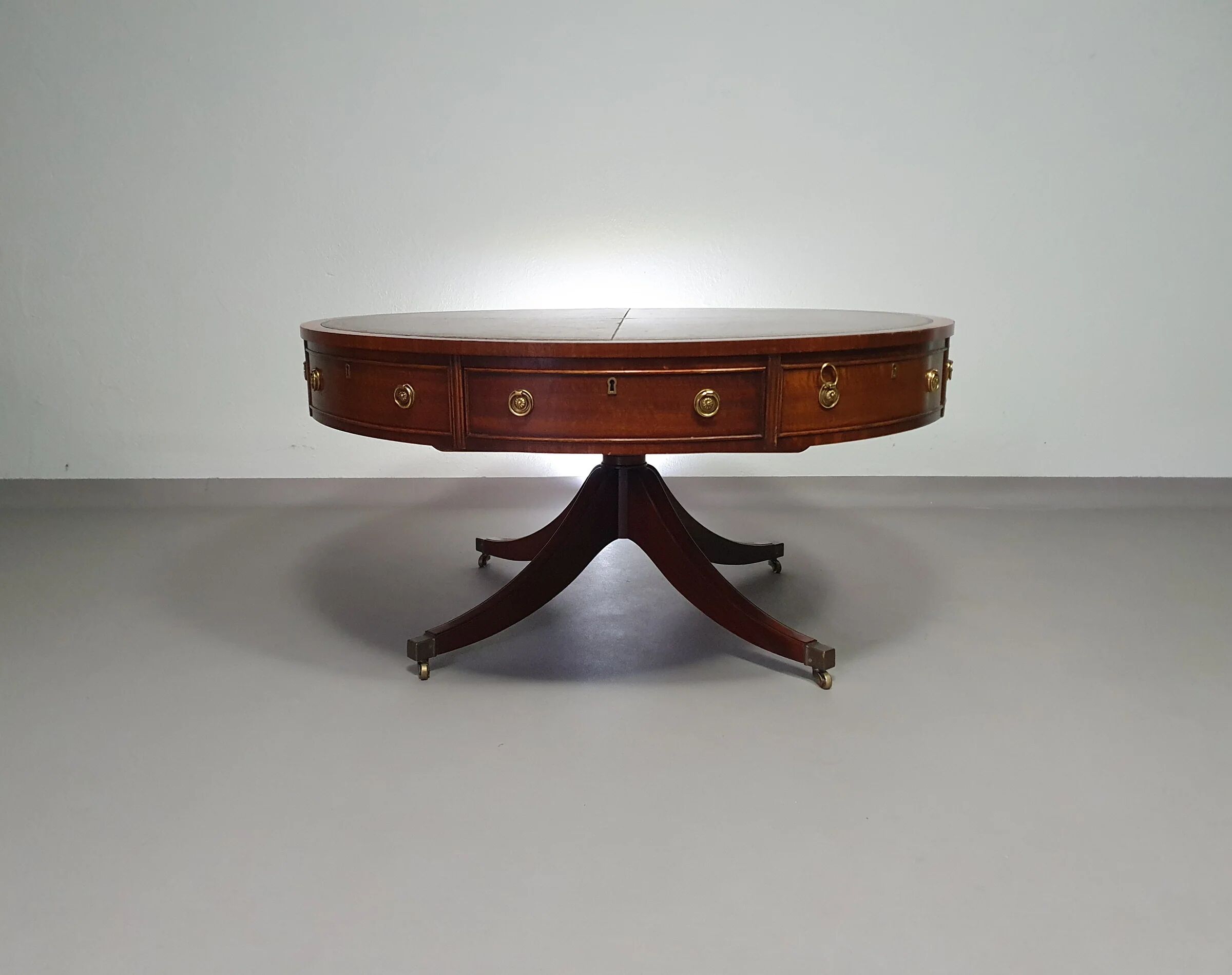 Table basse / table tambour victorienne « Heldense » en acajou avec plateau en cuir sur roulettes en laiton. Années 1980