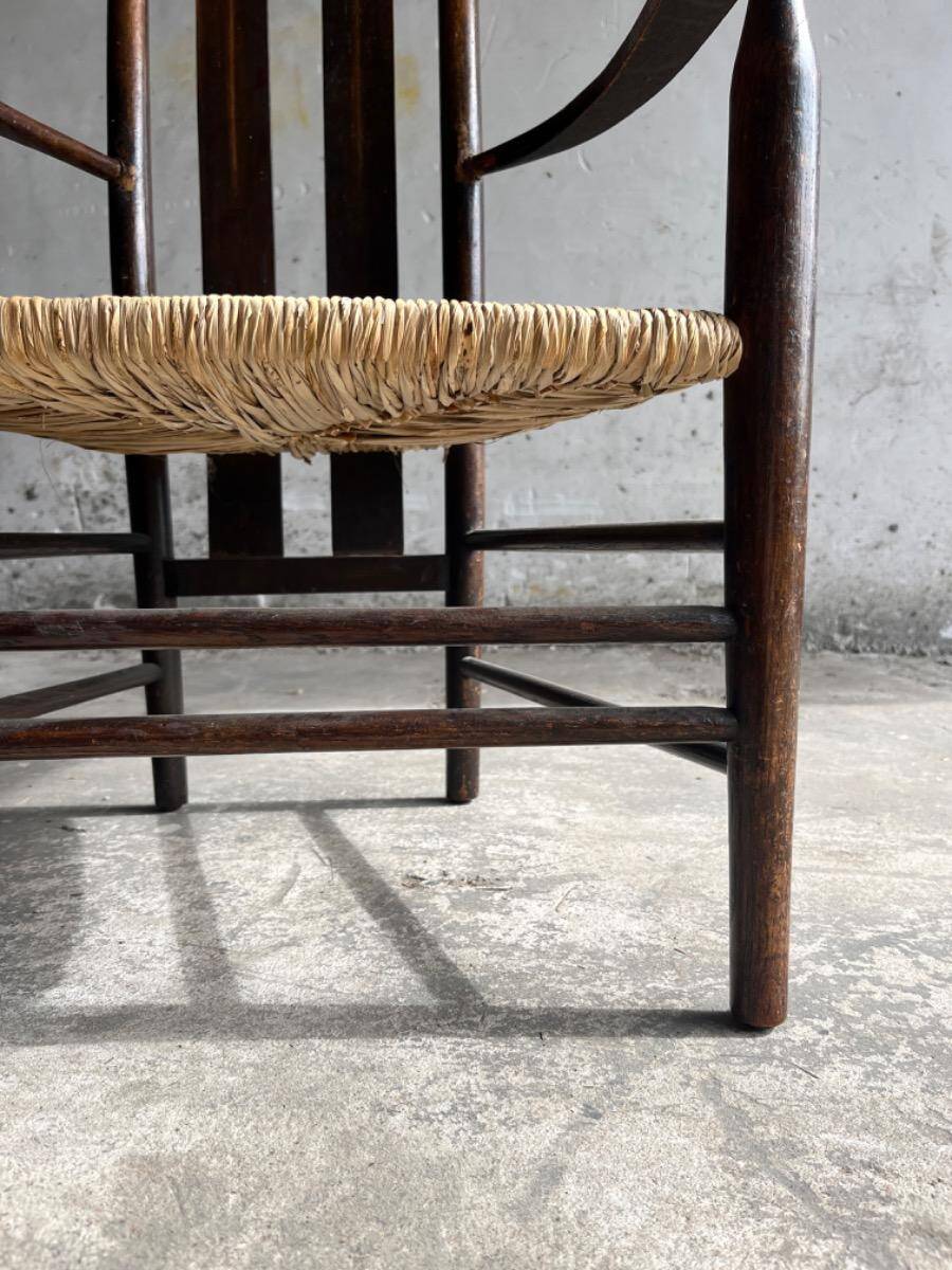 Dark brown solid wood Arts & Crafts armchair with natural rush seat and high back