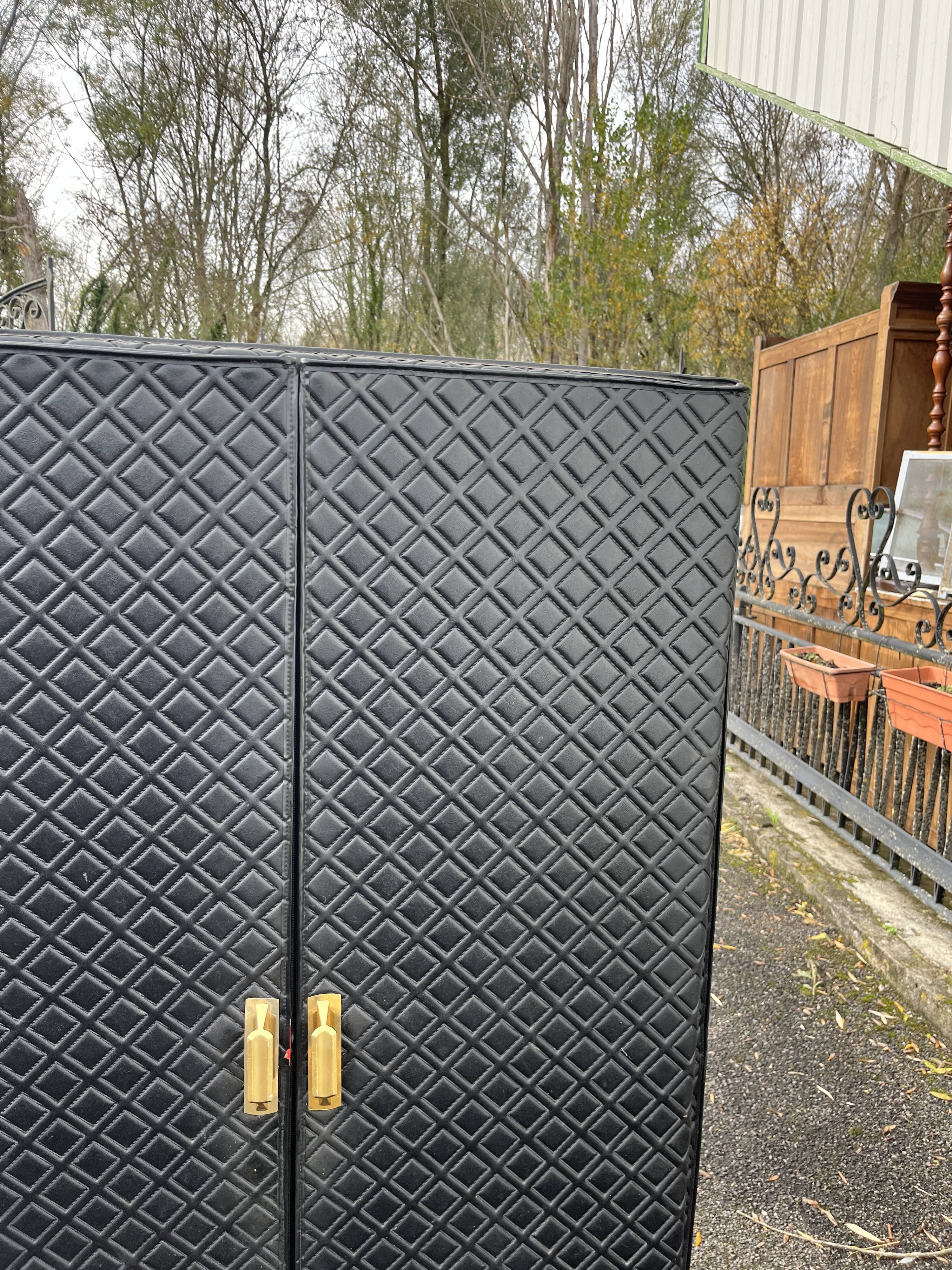 Contemporary wardrobe in black faux leather with diamond pattern and gold handles.