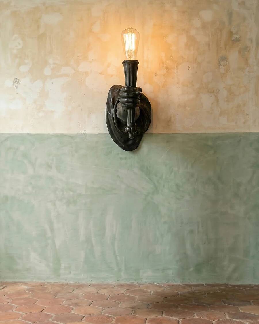 Wall lamp in iron shaped like an arm.