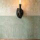Wall lamp in iron shaped like an arm.