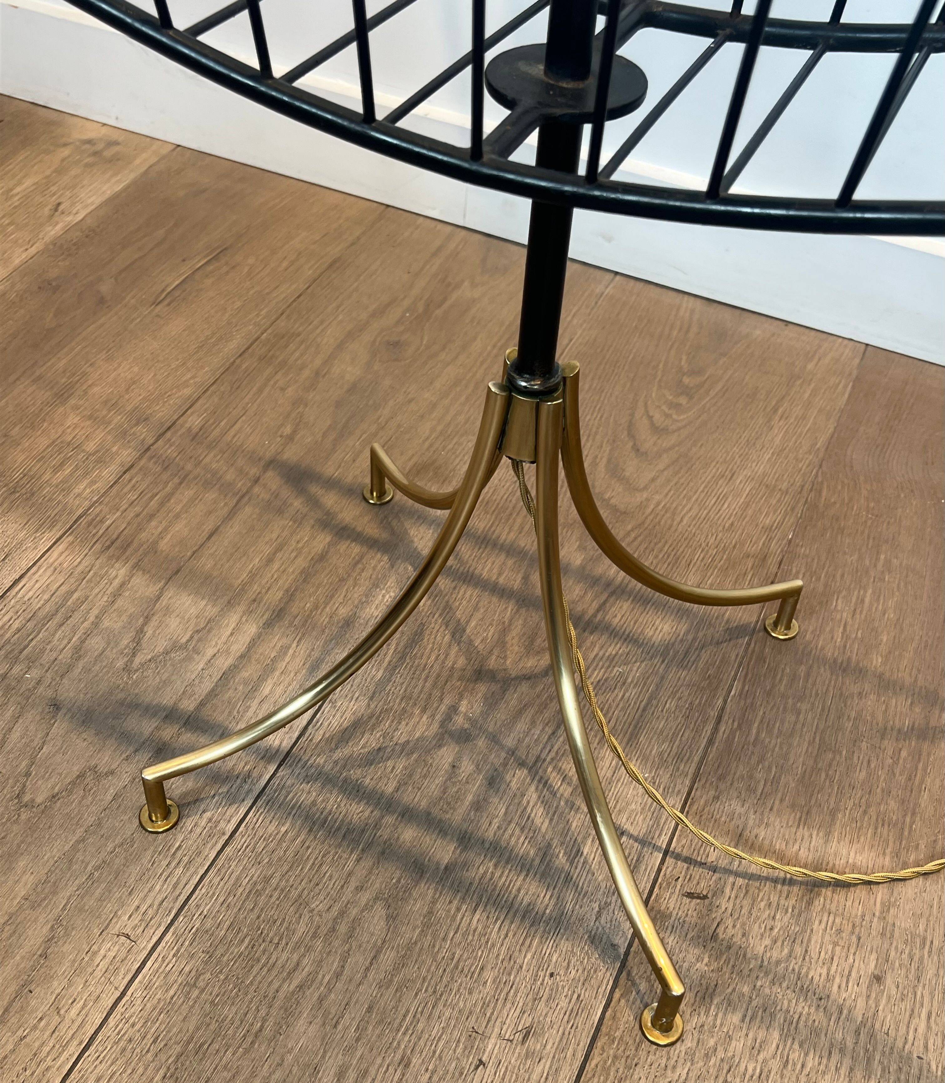 Designer floor lamp in black lacquered metal and brass, incorporating a magazine rack