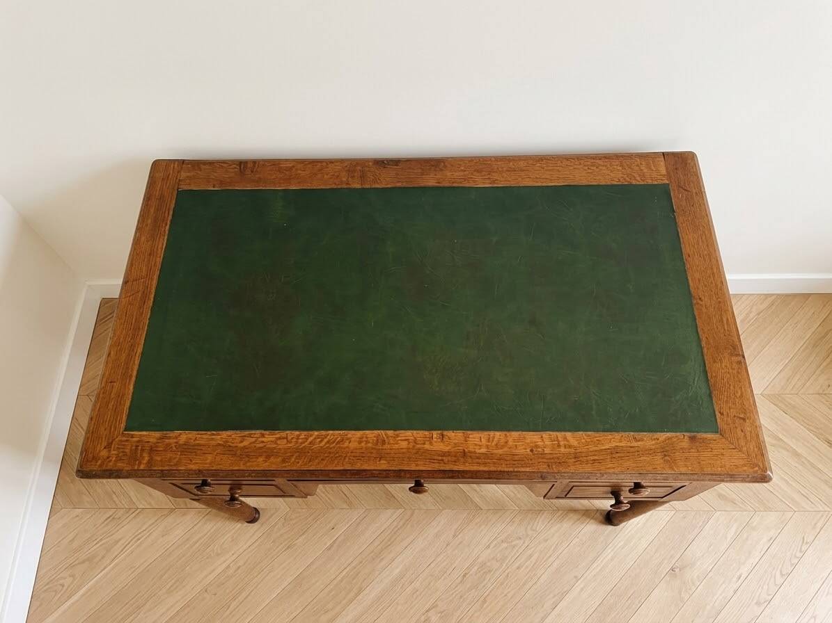 Antique wooden desk with a sloped top and green writing pad.