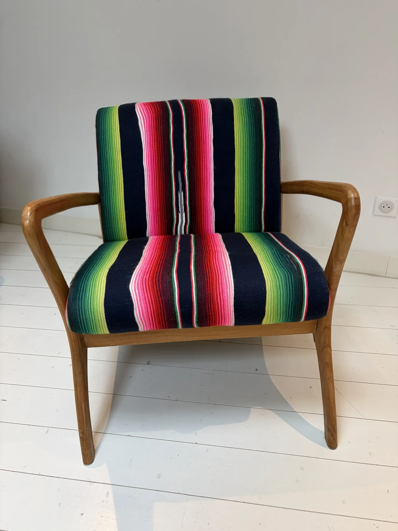 Scandinavian-style armchair in curved wood and colourful striped fabric.