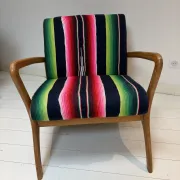 Scandinavian-style armchair in curved wood and colourful striped fabric.