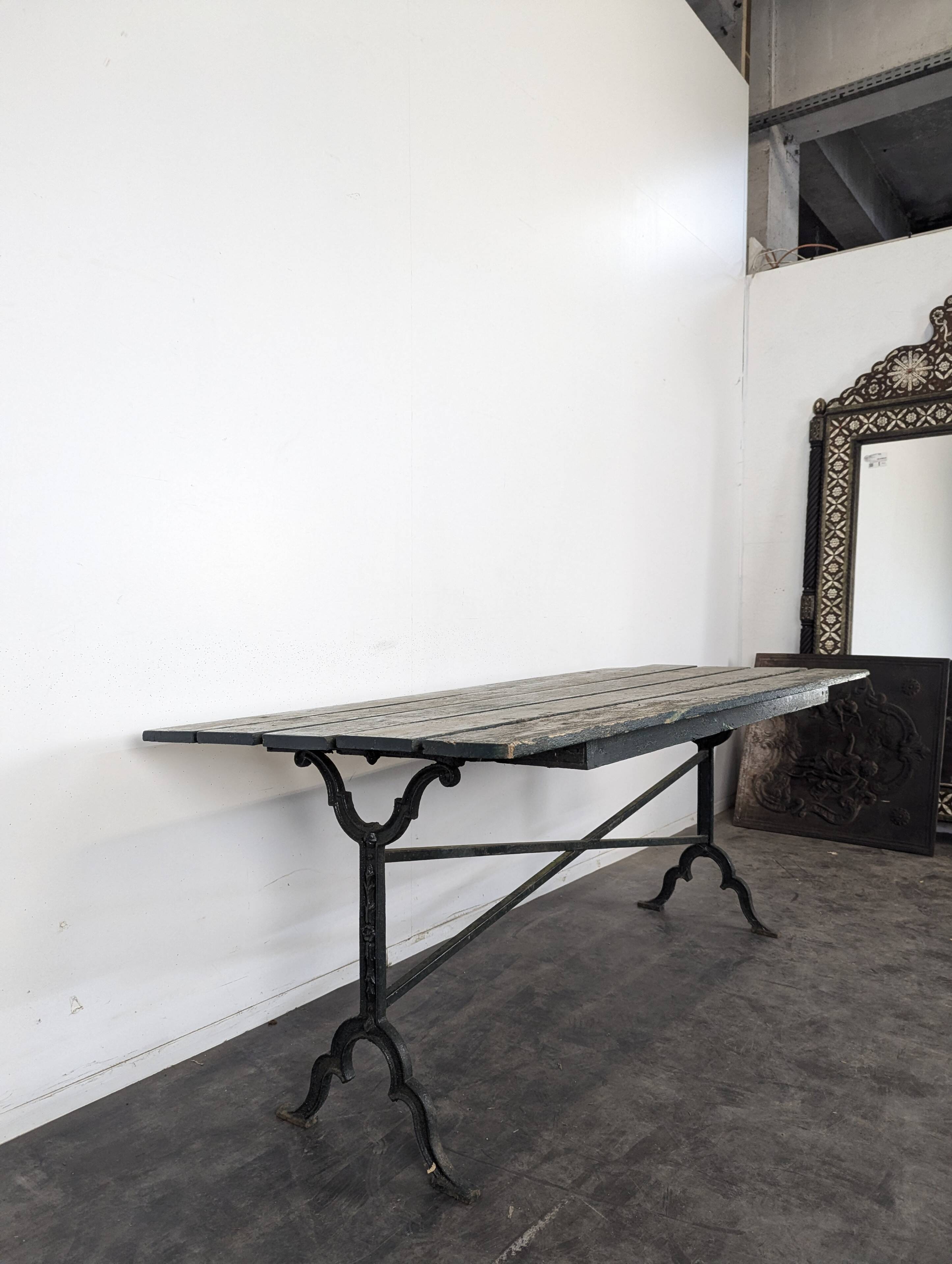 Garden table with a cast iron base and a green painted wooden top.