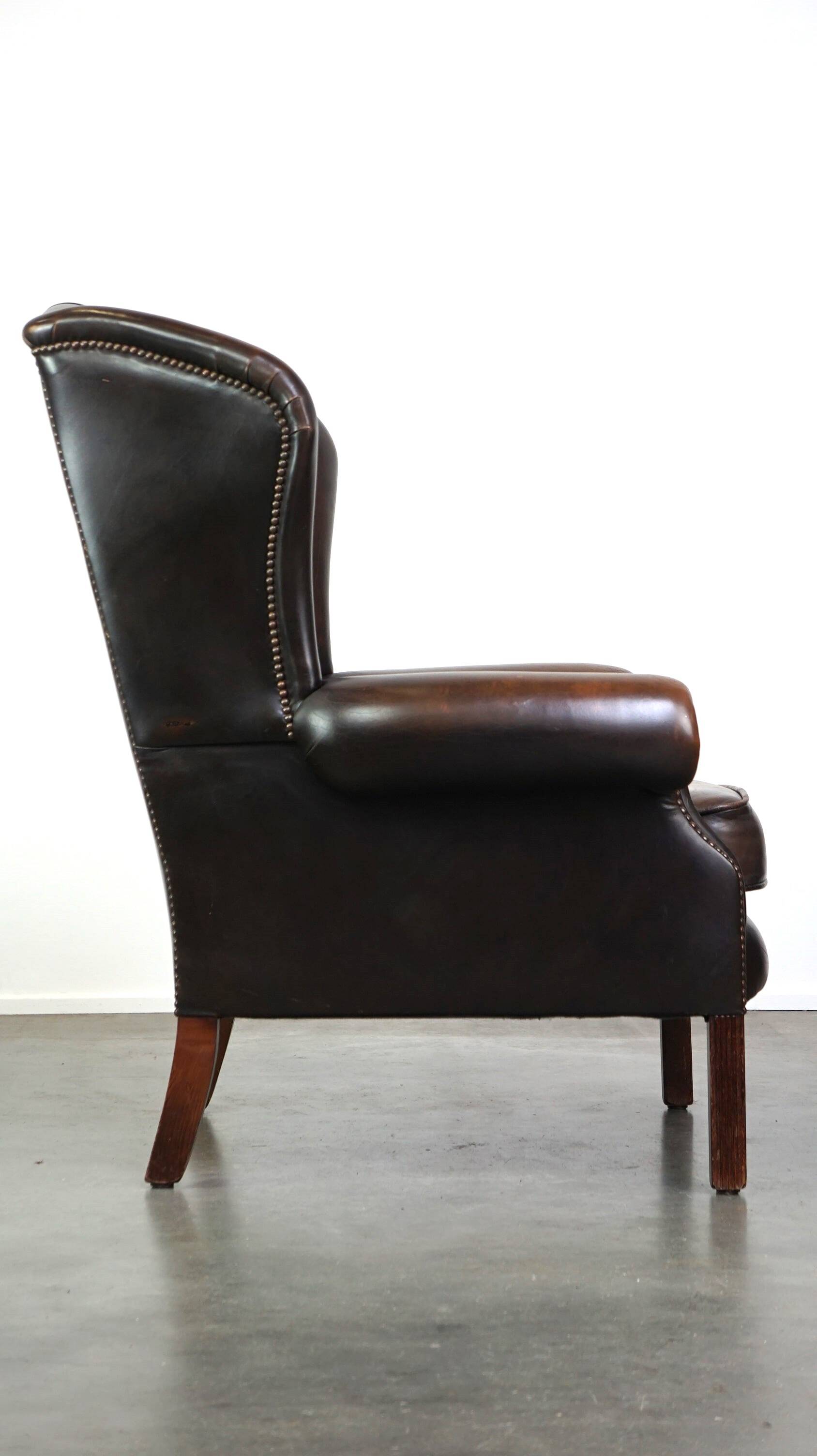 Chesterfield wing chair in dark brown leather with a luxurious appearance