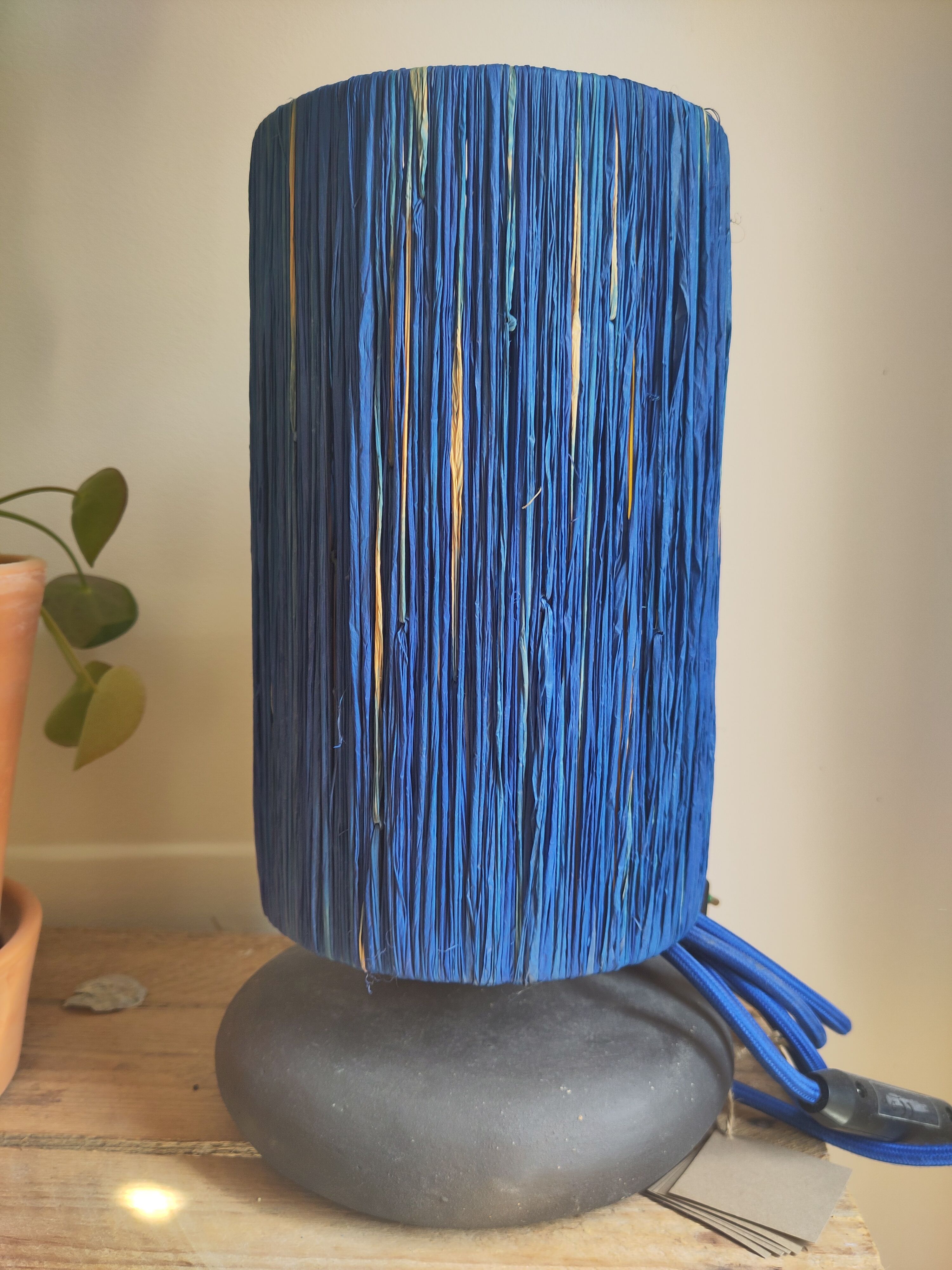 Table lamp in black stoneware and natural raffia.
