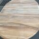 Round extendable dining table stripped in solid raw walnut with a central leg.