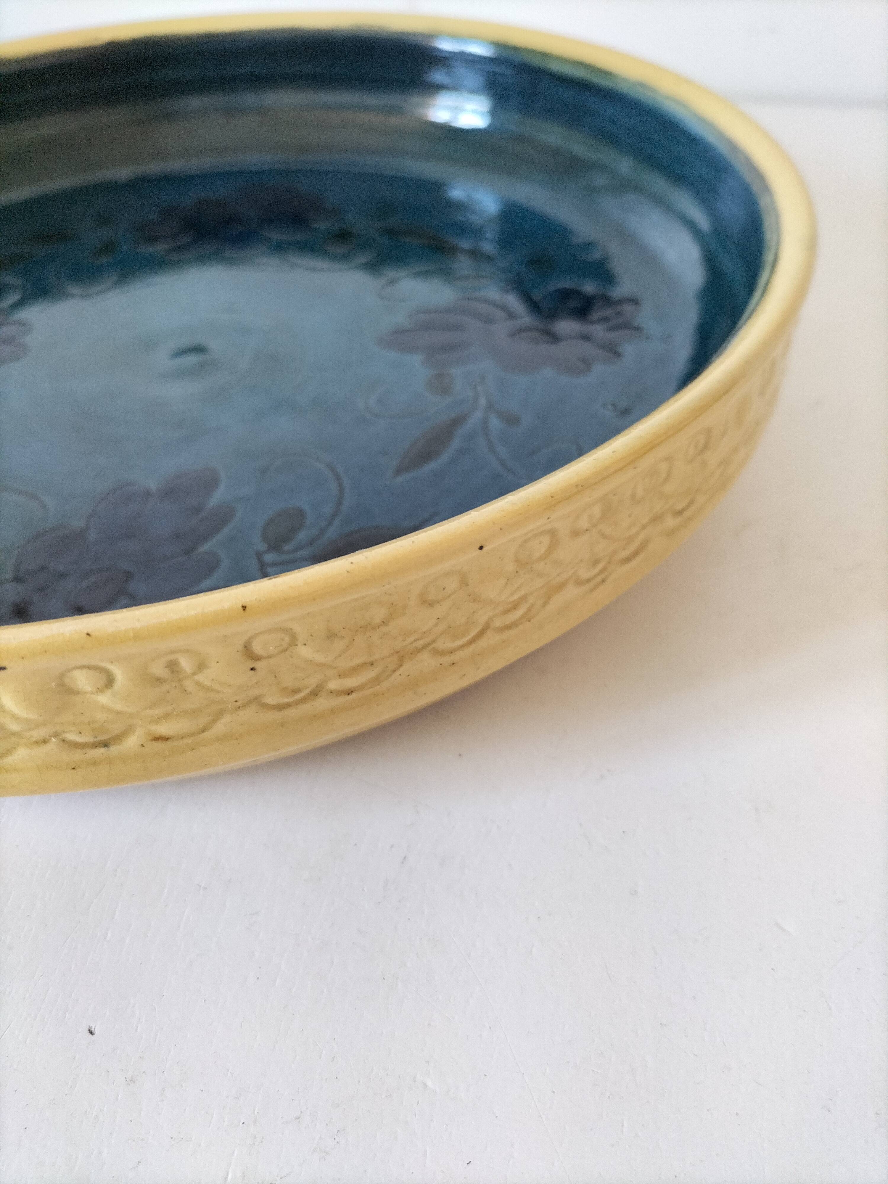 Blue floral glazed stoneware plate with a yellow rim.