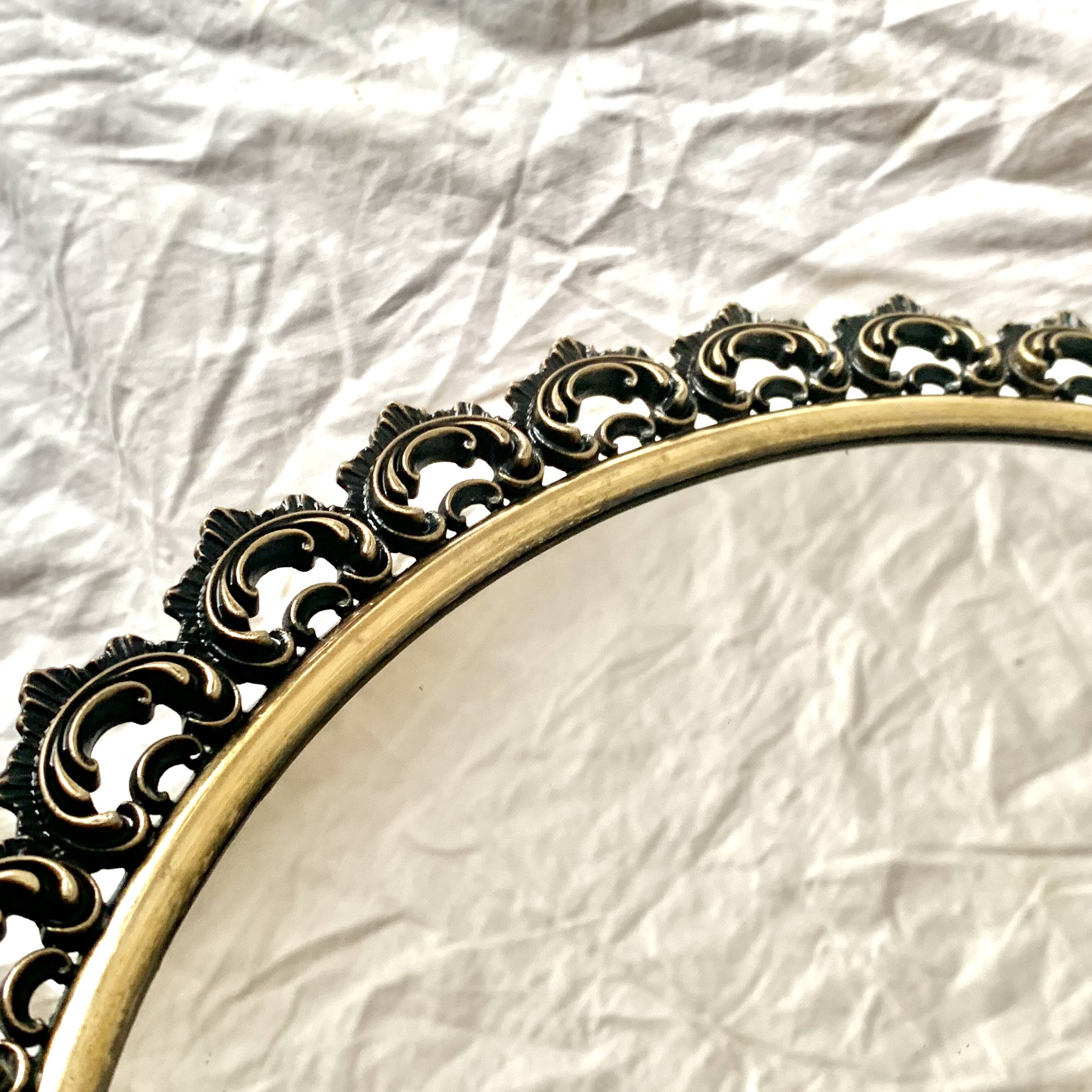 Old oval wall mirror in gilded brass
