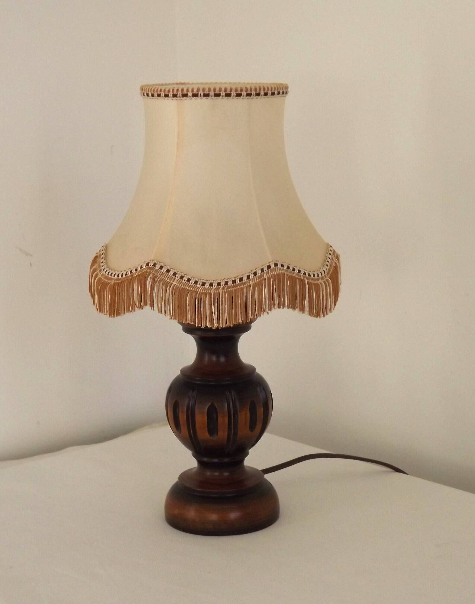 Mid-century French table lamp made of turned carved wood with a fringed shade.