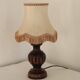 Mid-century French table lamp made of turned carved wood with a fringed shade.