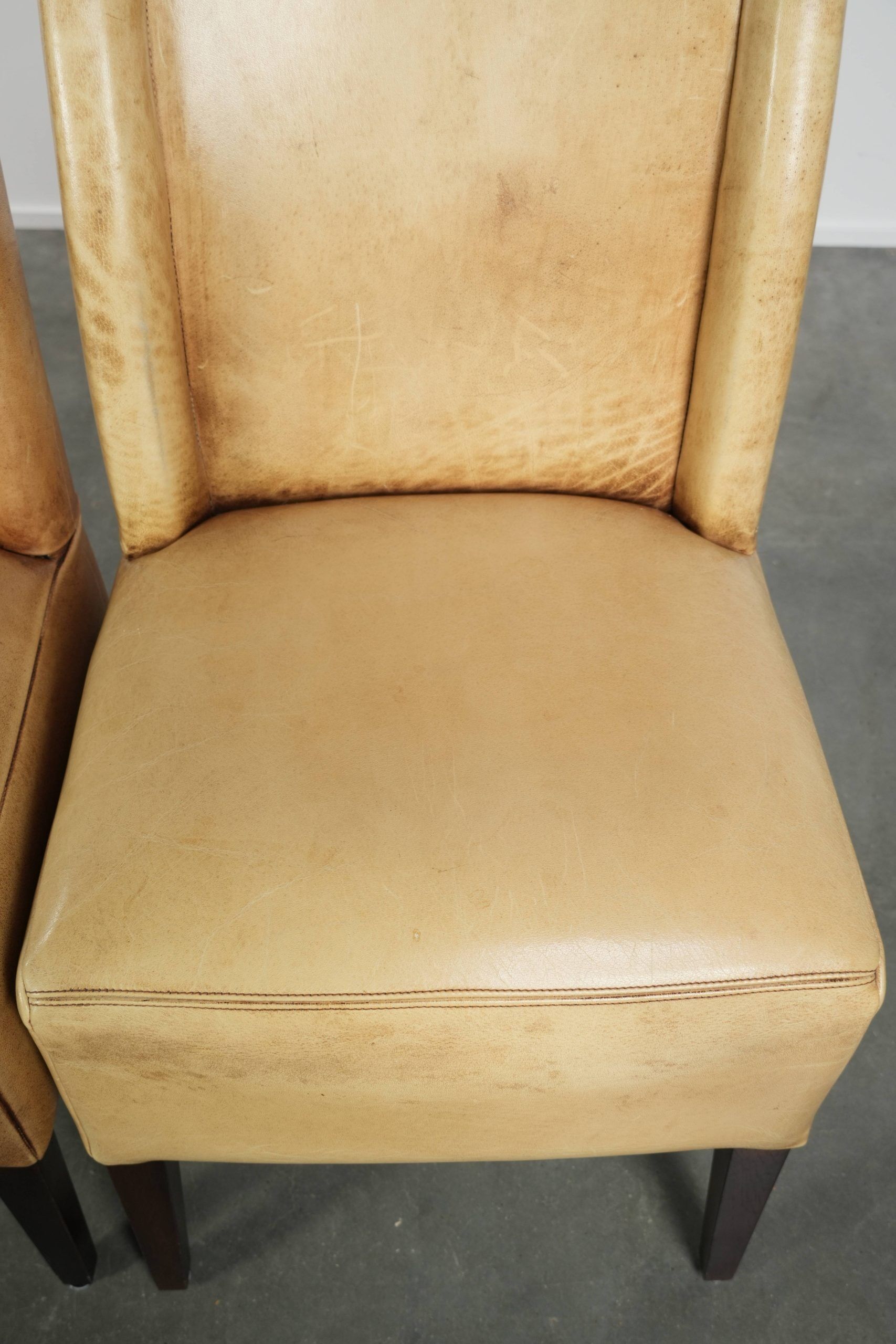 Ensemble de quatre chaises de salle à manger en cuir de vache avec un siège confortable et un dossier haut.