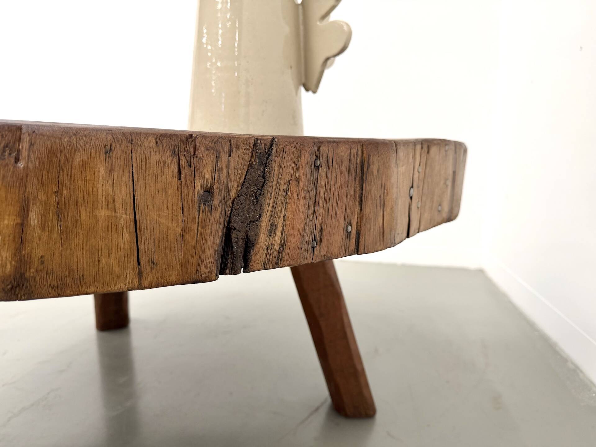 Brutalist coffee table in solid teak, monolithic slab, tripod base.