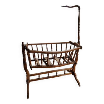 Wooden cradle in walnut with a sign collar at the top.