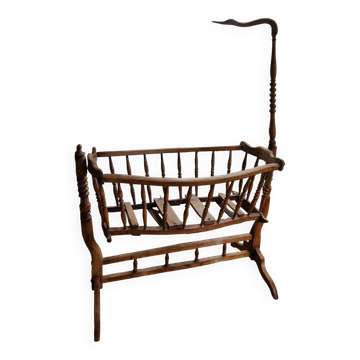 Wooden cradle in walnut with a sign peak.