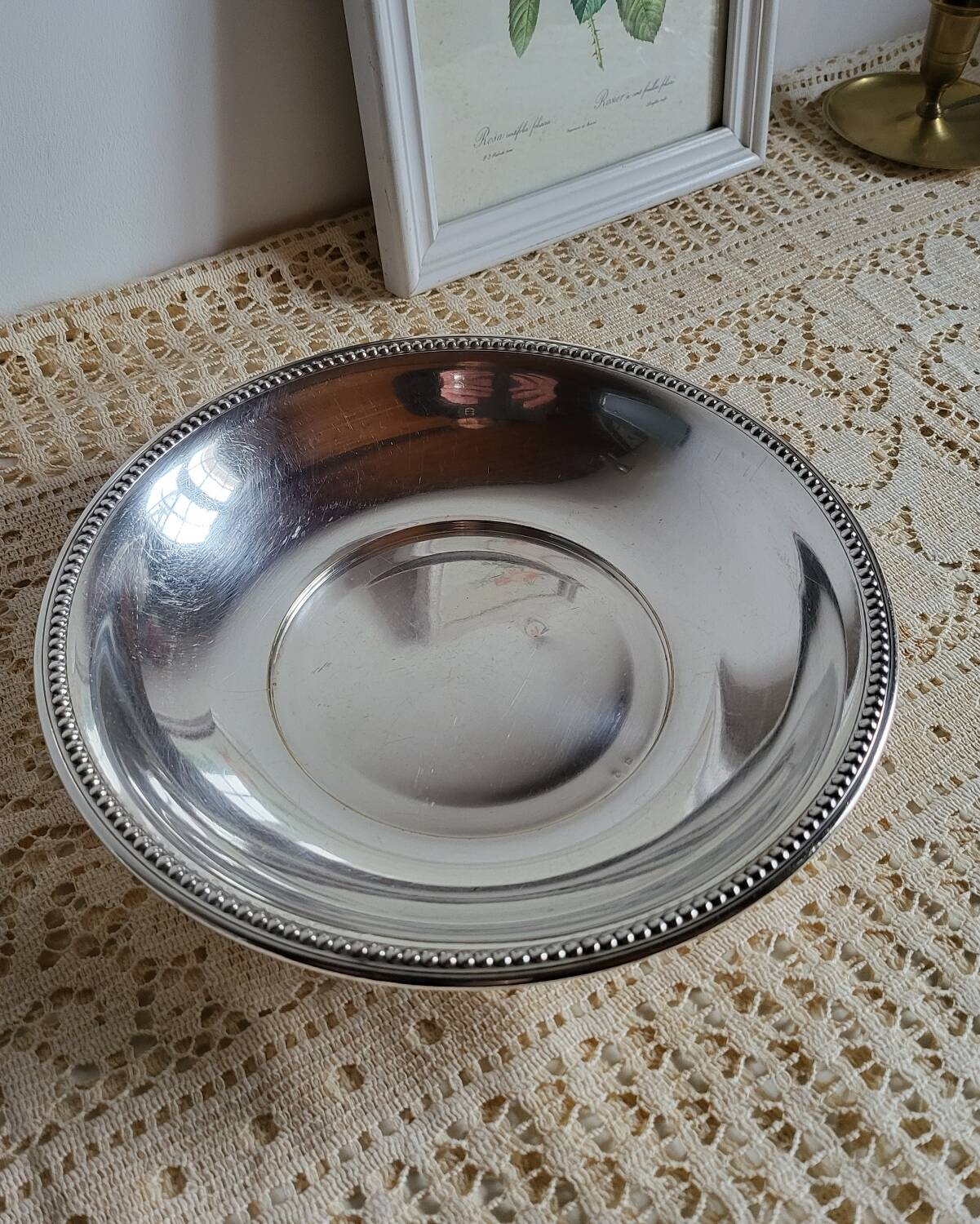 Shallow round metal plate with pearl bead decoration.