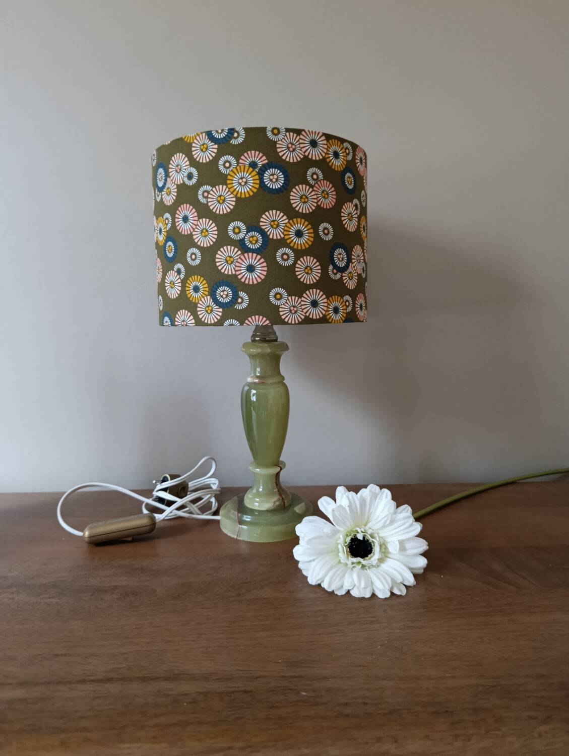 Table lamp with light green onyx base, fabric shade with a khaki background.