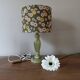 Table lamp with light green onyx base, fabric shade with a khaki background.