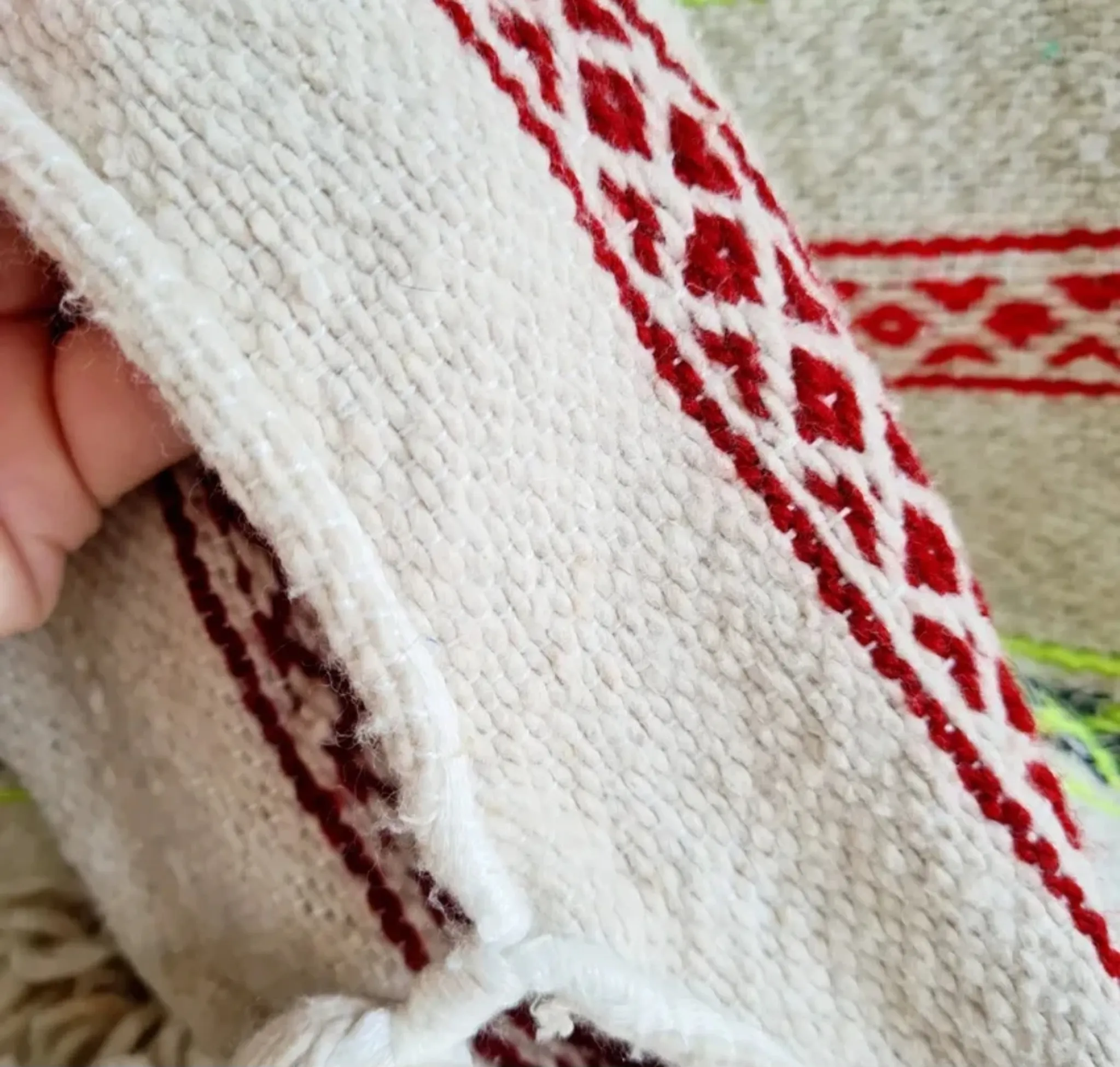 Moroccan plaid made of handwoven wool, decorated with stripes and pom poms.