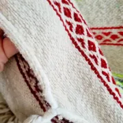 Moroccan plaid made of handwoven wool, decorated with stripes and pom poms.