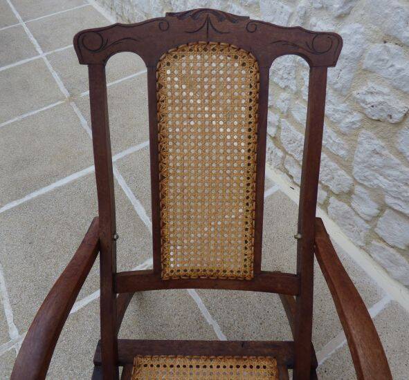 Antique folding chair with caned seat and backrest made of wood.
