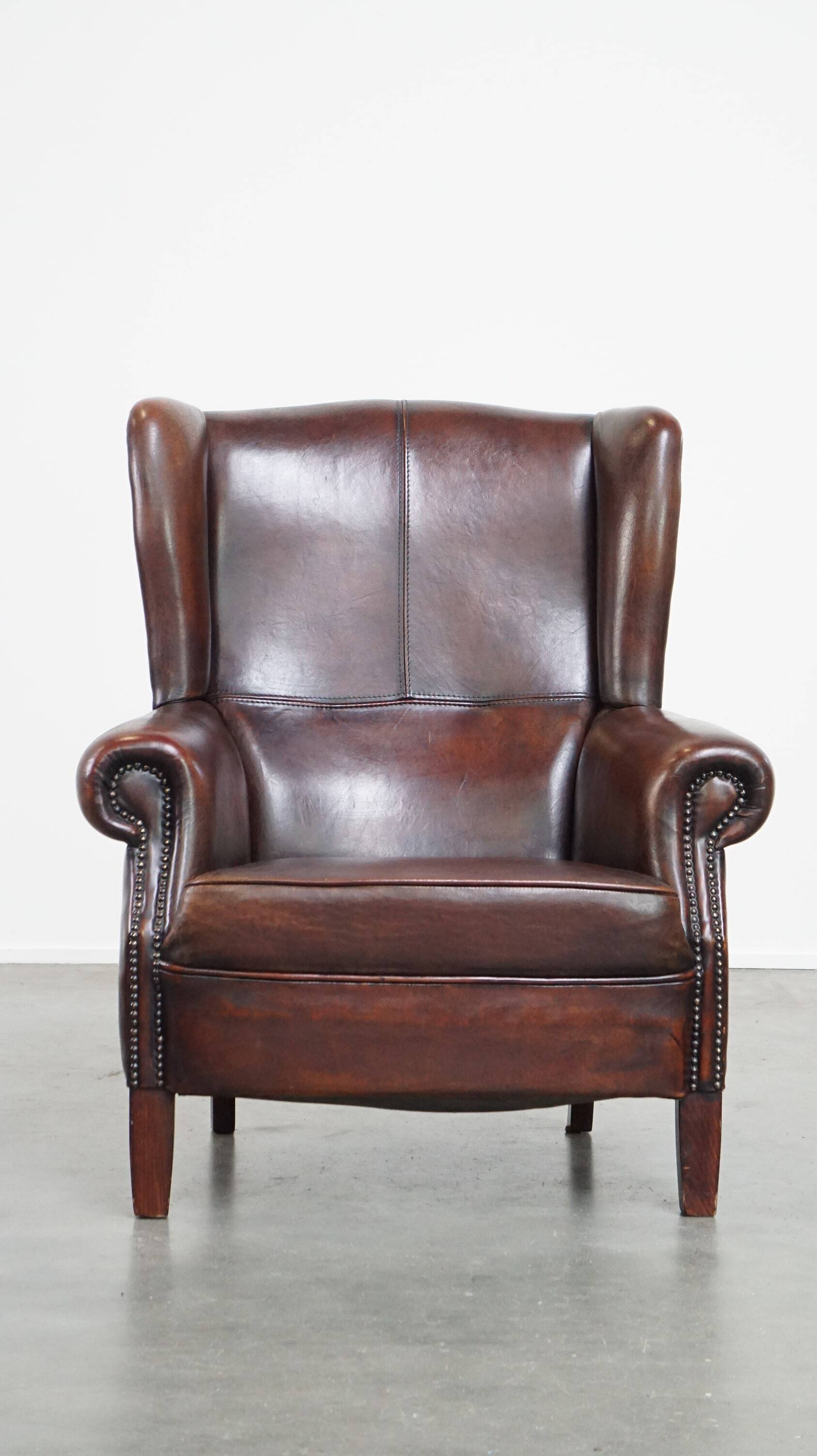 Fauteuil à oreilles confortable et bien entretenu en cuir de mouton