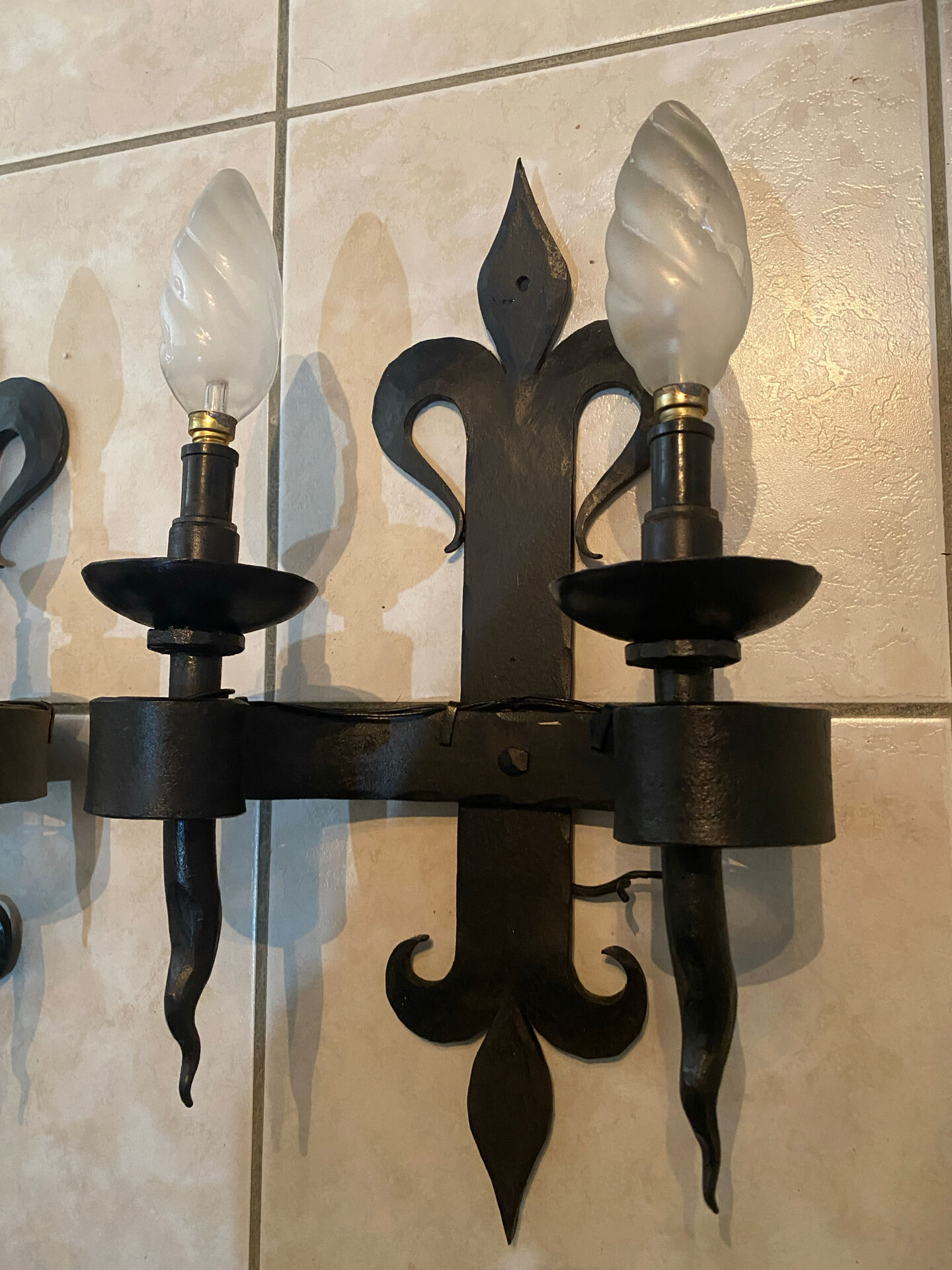 Pair of wrought iron wall lights in fleur-de-lis château style.