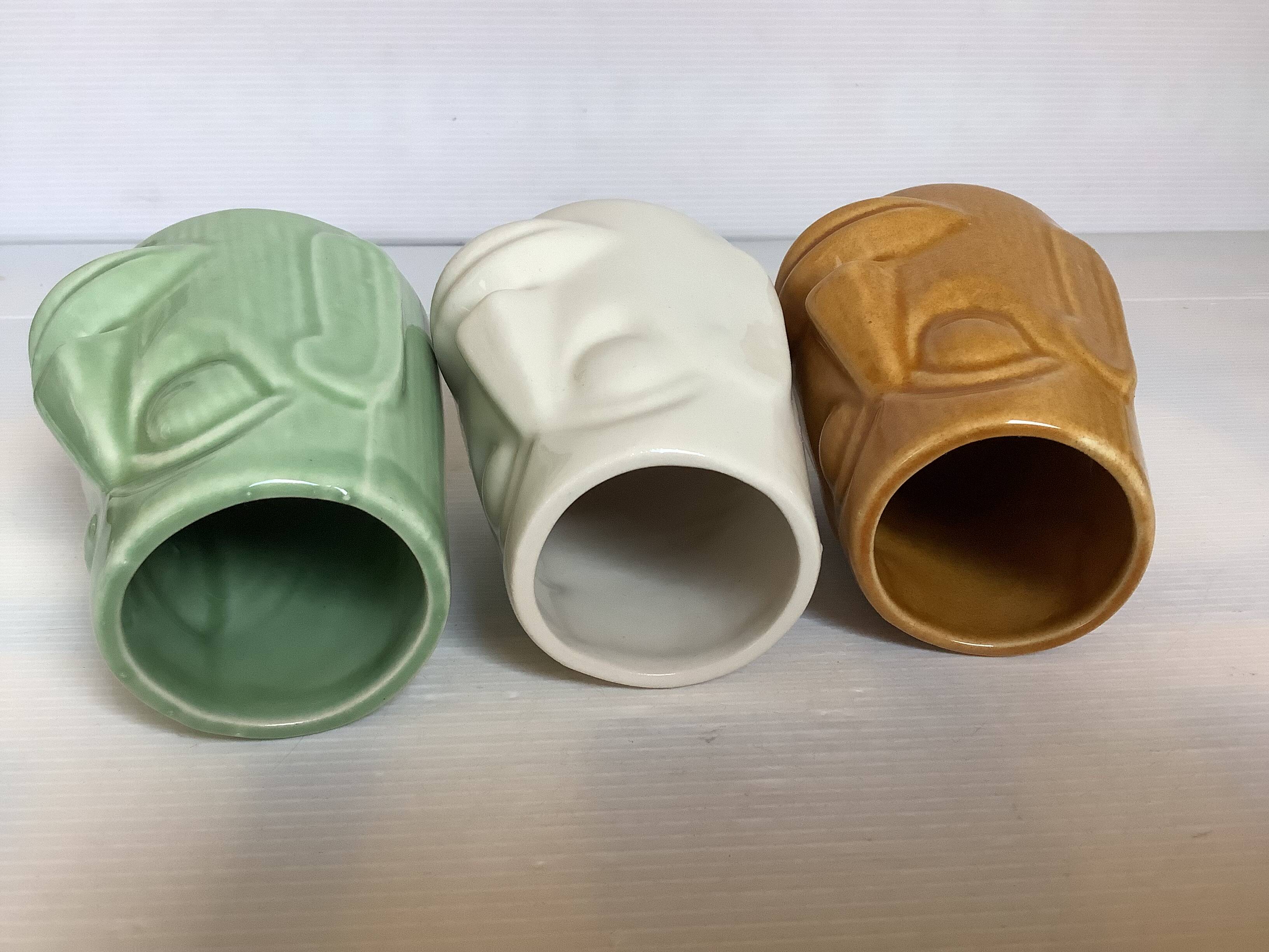 Set of three small Moai-style head vases.